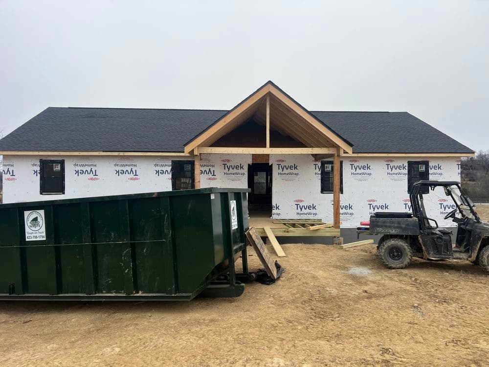 New home construction with Tyvek wrapping and a construction dumpster on site.