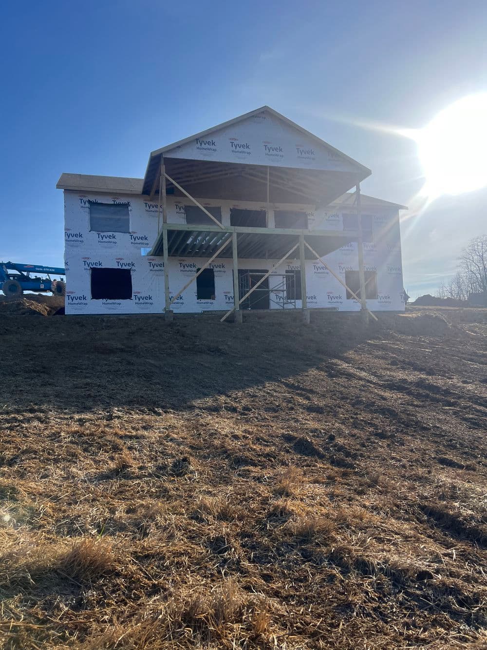 Newly constructed home under construction with Tyvek wrap and sunny sky.