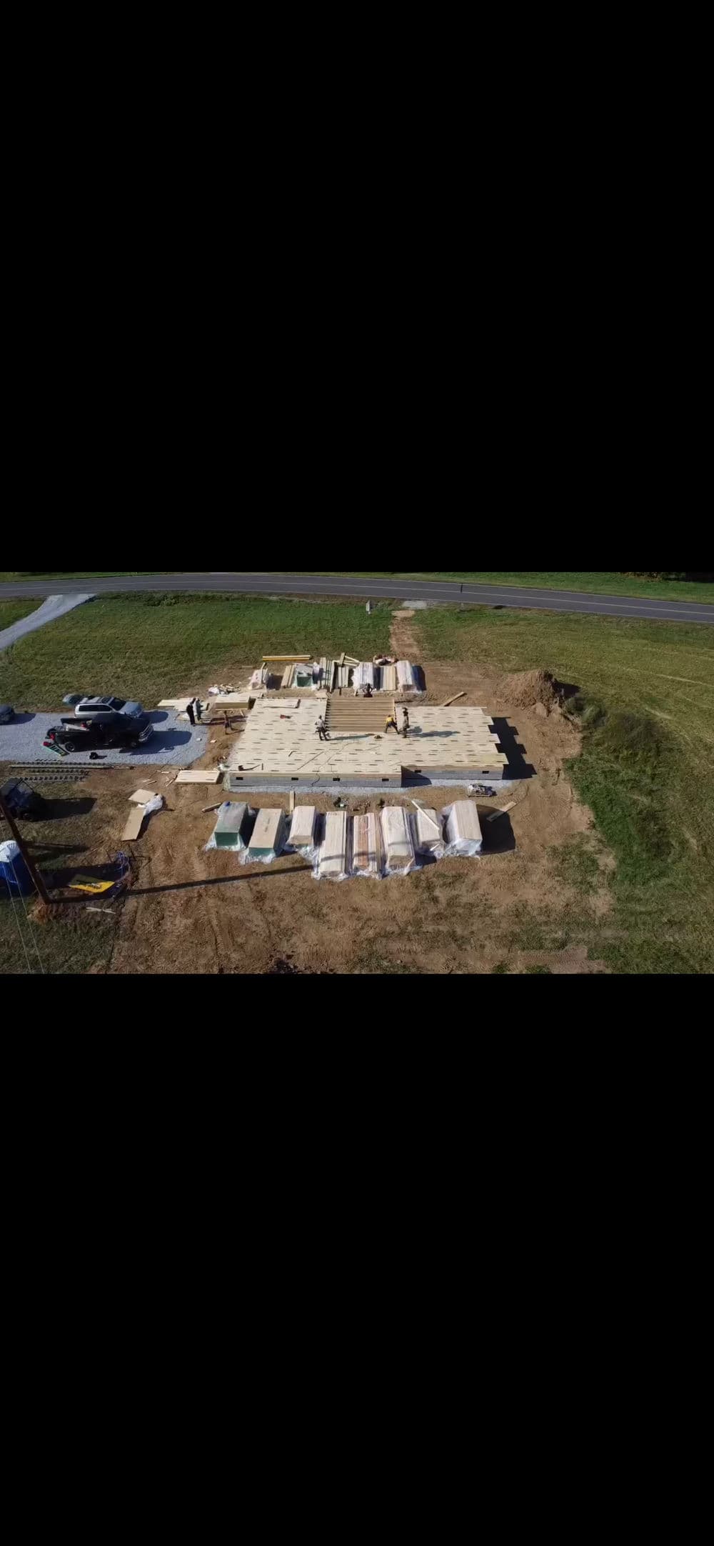 Aerial view of a construction site with stacked building materials and foundation laid.