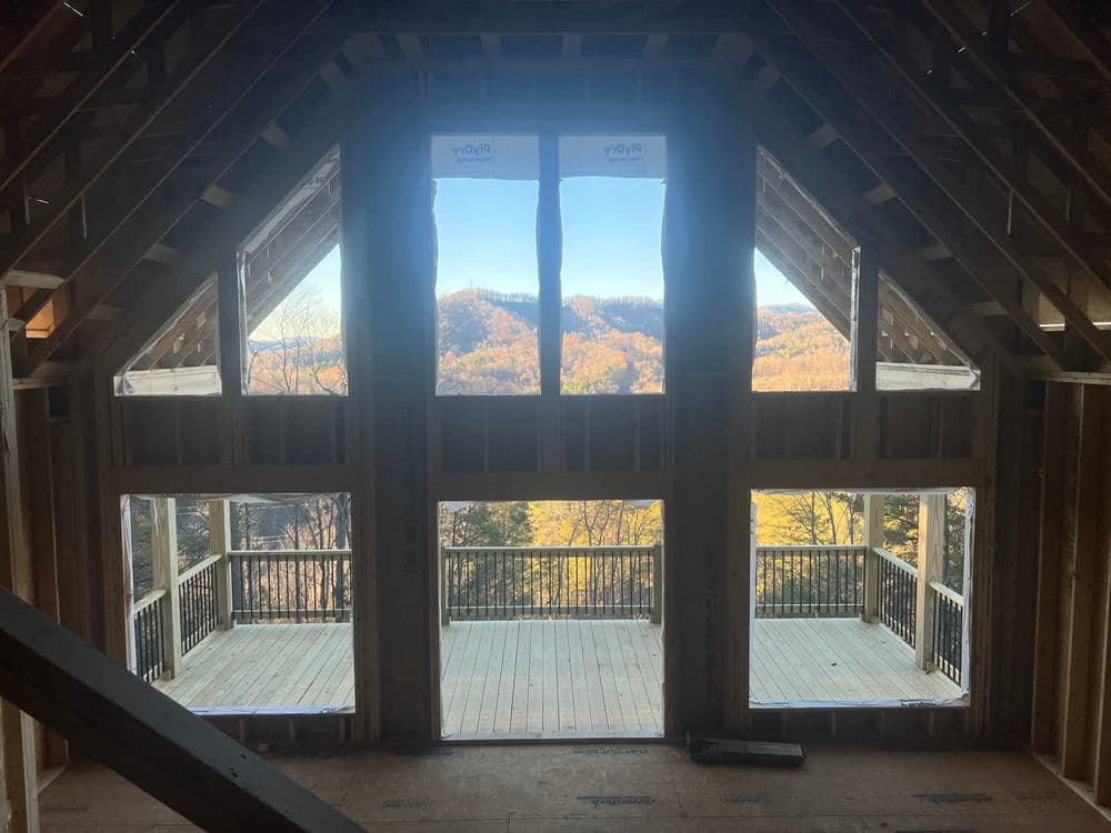 Interior view of a home under construction with large windows showcasing a scenic mountain landscape.