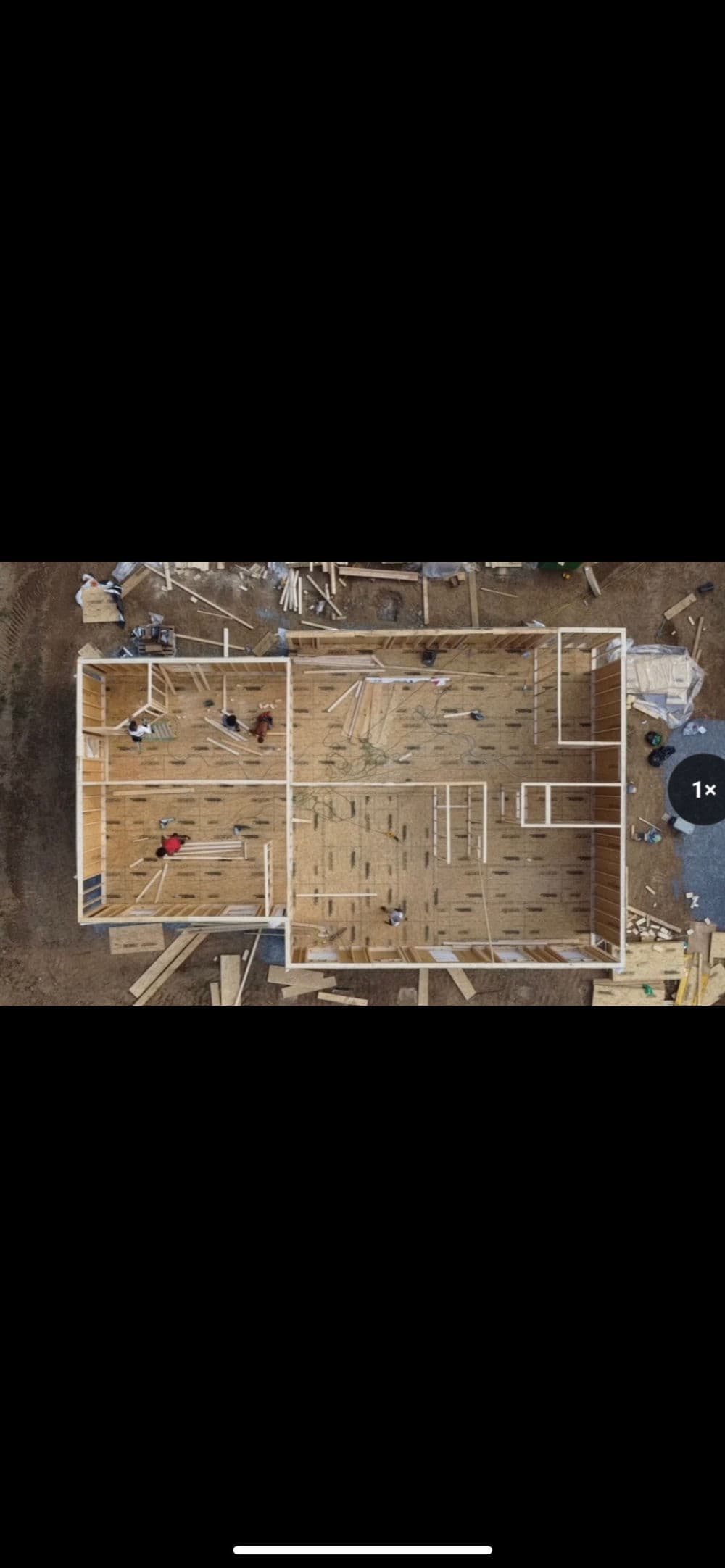 Aerial view of a house under construction, showing workers and framed walls.
